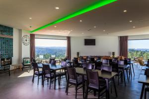 un comedor con mesas, sillas y luces verdes en Enigma - Nature & Water Hotel, en São Teotónio