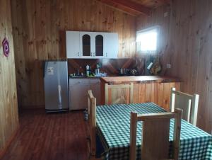 a kitchen with a refrigerator and a table and chairs at Cabañas encanto de Chovellen in Pelluhue