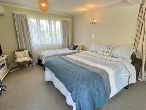 a bedroom with two beds and a chair in it at Feel at Home in Tauranga