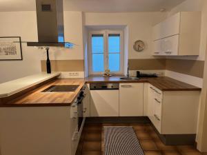 een keuken met witte kasten, een gootsteen en een raam bij Rosenberger I in Hopfgarten im Brixental +13 foto's