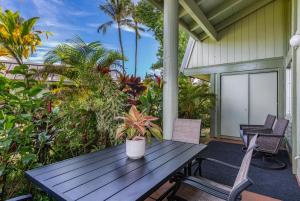 a wooden picnic table on a porch with chairs at Puamana 26B in Princeville