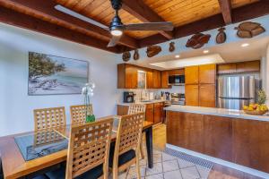 a kitchen with wooden cabinets and a table and chairs at Puamana 26B in Princeville