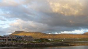 a house on the shore of a lake with mountains in the background at Óstán Oileán Acla in Achill Sound