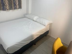 a bed in a room with a yellow chair at Kiwi Nest in Auckland