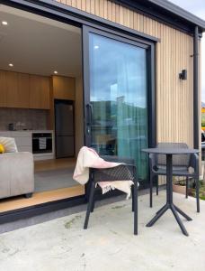 a glass house with a patio and a table at Summit View Studio Jacks Point in Queenstown Airport
