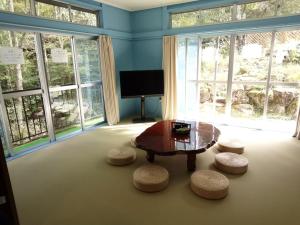 a living room with a table and stools and windows at コテージ遊泊るり渓 in Habu