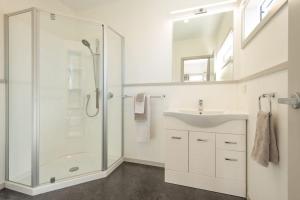 ein weißes Badezimmer mit Dusche und Waschbecken in der Unterkunft Fairway views entire home in Matamata