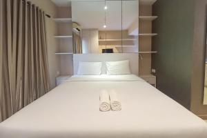 ein Schlafzimmer mit einem Bett mit zwei Schuhen drauf in der Unterkunft Elegant and Cozy Studio Student Park Apartment By Travelio in Seturan