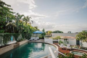 una piscina al aire libre con sillas y sombrilla en Alivio Hotel Cairns, en Cairns