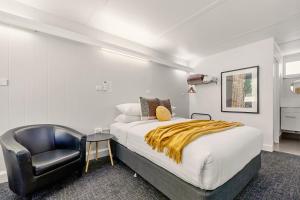 een slaapkamer met een bed en een zwarte stoel bij Bridgewater Motel Victoria-24 HourCheck-In in Bridgewater-on-Loddon