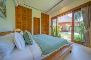 ein Schlafzimmer mit einem Bett und einem großen Fenster in der Unterkunft Villa Lea - 5BR luxury oasis in Seminyak with pool in Kerobokan