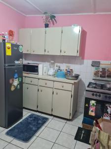 a kitchen with white cabinets and a black refrigerator at Linstead AirB&B Crescent Avenue in Linstead