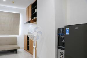 a fan in a room next to a refrigerator at Minimalist and Cozy 1BR Patraland Urbano Apartment By Travelio in Bekasi