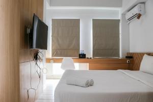 a bedroom with a bed and a flat screen tv at Minimalist and Cozy 1BR Patraland Urbano Apartment By Travelio in Bekasi
