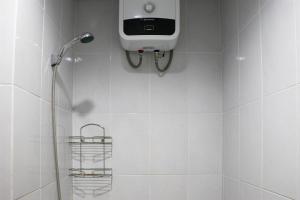 a bathroom with a shower with a soap dispenser on the wall at Minimalist and Cozy 1BR Patraland Urbano Apartment By Travelio in Bekasi +7 photos