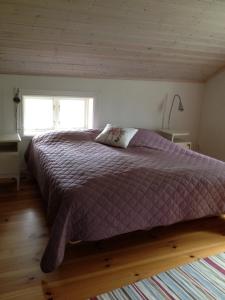 um quarto com uma cama com um edredão roxo e uma janela em Stuga Linnebråten em Värnamo