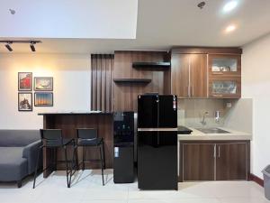 PampangにあるWarm and Cozy 2BR Vida View Makassar Apartment By Travelioのキッチン(黒い冷蔵庫、カウンター付)