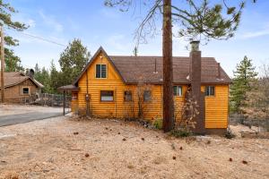 ein Holzhaus mit einem Baum davor in der Unterkunft The Fawnskin Hideaway, HUGE Backyard, BBQ & Patio! in Fawnskin