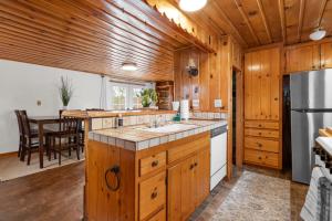 eine Küche mit Holzschränken und ein Esszimmer in der Unterkunft The Fawnskin Hideaway, HUGE Backyard, BBQ & Patio! in Fawnskin