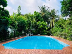 ein blauer Swimmingpool in einem Garten mit Bäumen in der Unterkunft The Backyard 28 in Klong Toi