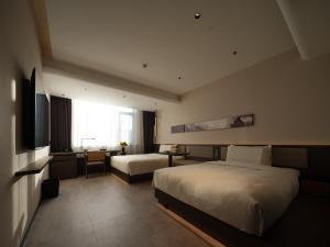 a hotel room with two beds and a television at Atour Hotel Dalian Zhongshan Plaza Lu Xun Road in Dalian
