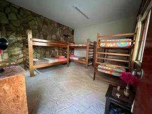 a room with three bunk beds and a stone wall at Stone House Mancora in Máncora