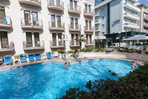 a swimming pool in front of a building at Hotel Ambassador in Rimini