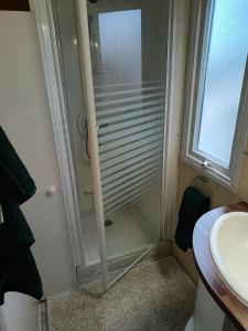 a glass shower in a bathroom with a sink at CAMPING LE CLOS DU THYM in Argelès-sur-Mer
