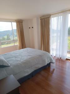 a bedroom with a bed and a large window at Villa Graciela II in Paipa