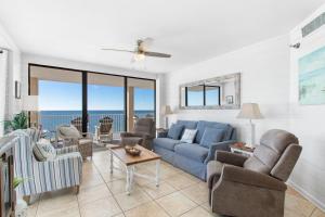 Una sala de estar con un sofá azul y sillas. en Bluewater 1501, en Orange Beach 27 fotos más