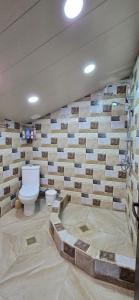 a bathroom with a toilet and a brick wall at Guest House Tamta in Kazbegi