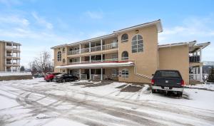 un edificio con coches aparcados en un aparcamiento cubierto de nieve en Vista, en Fairmont Hot Springs