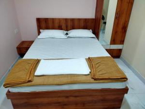 a bed with white sheets and a wooden headboard at Mandara Comforts Hotel in Bengaluru