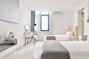 a white room with two beds and a mirror at Sanya Haishi Swimming Pool Design Hotel in Sanya