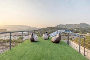 3 persone sedute su un balcone con vista sulle montagne di Alaya Stays 4 BHK with Pvt Plunge pool - Lumbini a Udaipur