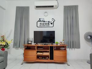 a living room with a television on a wooden entertainment center at SS Ipoh Comfort Homestay - Taman Bertuah in Ipoh
