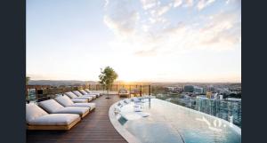 布里斯班Luxury Peppers Infinity Pool Stylish with 2BD & 1C Park的带沙发的阳台和建筑物上的游泳池
