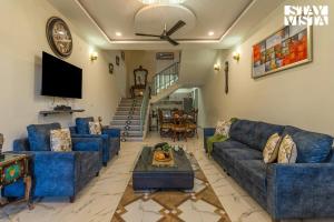 ein Wohnzimmer mit blauen Sofas und einem Fernseher in der Unterkunft StayVista at Pinecrest Manor - Outdoor Jacuzzi in Kasauli