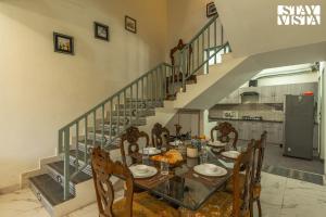 ein Esszimmer mit Tisch und Stühlen und einer Treppe in der Unterkunft StayVista at Pinecrest Manor - Outdoor Jacuzzi in Kasauli