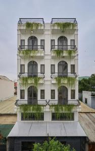 Un edificio alto y blanco con plantas en los balcones. en Green Riverside Hotel & Apartment, en Ho Chi Minh