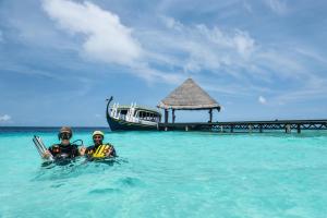 two people in the water near a boat in the ocean at Adaaran Club Rannalhi - All Inclusive - 45 Minutes away from Male by Speedboat in South Male Atoll