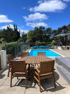 a wooden table and chairs next to a swimming pool at Kitchen Garden Studio Spa - Bed and Breakfast in Auckland