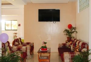 a living room with couches and a flat screen tv at RedDoorz @ LS Suites Poblacion Culasi Antique in Jalandoni