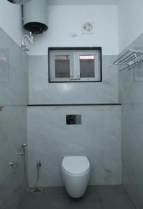 a white bathroom with a toilet and a window at Kaveri Homestay in Suntikoppa
