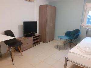 ein Wohnzimmer mit einem TV und 2 Stühlen in der Unterkunft City Studio Kavala in Kavala