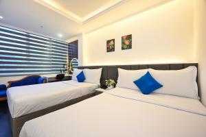 2 letti in camera d'albergo con cuscini blu di Ruby Saigon Hotel - Ben Thanh ad Ho Chi Minh