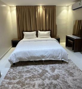 a bedroom with a large white bed and a rug at سما المملكة للشقق المخدومة- اقتصادي in Riyadh