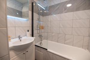 a white bathroom with a sink and a bath tub at Le 1521 STUDIO in Sélestat +28 photos