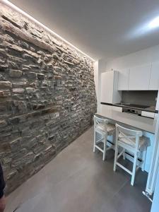 a kitchen with a stone wall and a table and chairs at Un balcone sul lago in Torno +25 photos