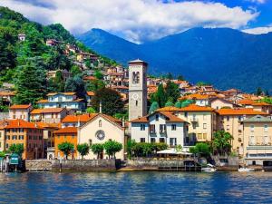 a town with a clock tower next to a body of water at Un balcone sul lago in Torno